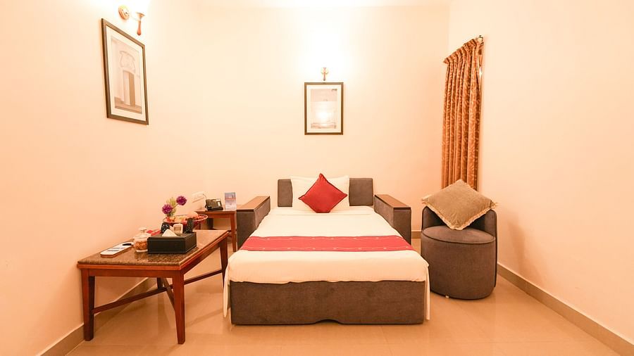 Image of a single bed along with a couch next to it and a table on its other side