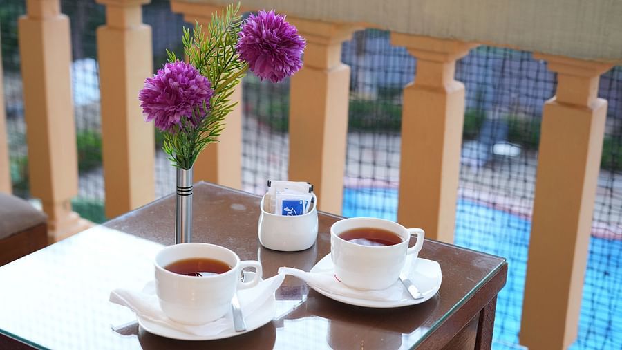 A couple of teacups and a mini vase placed on the teapoy