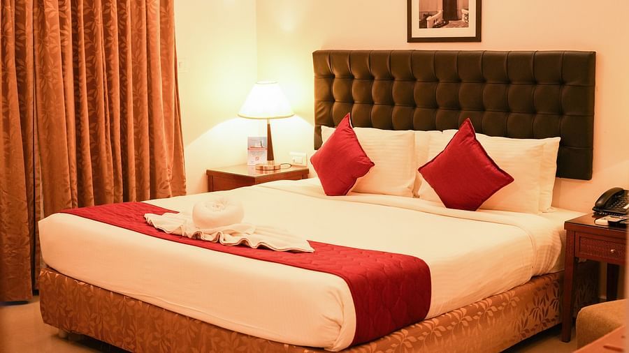 Image of Grandeur Pool View Suite featuring a plush bed with a large headboard and a nightstand with a lamp on it