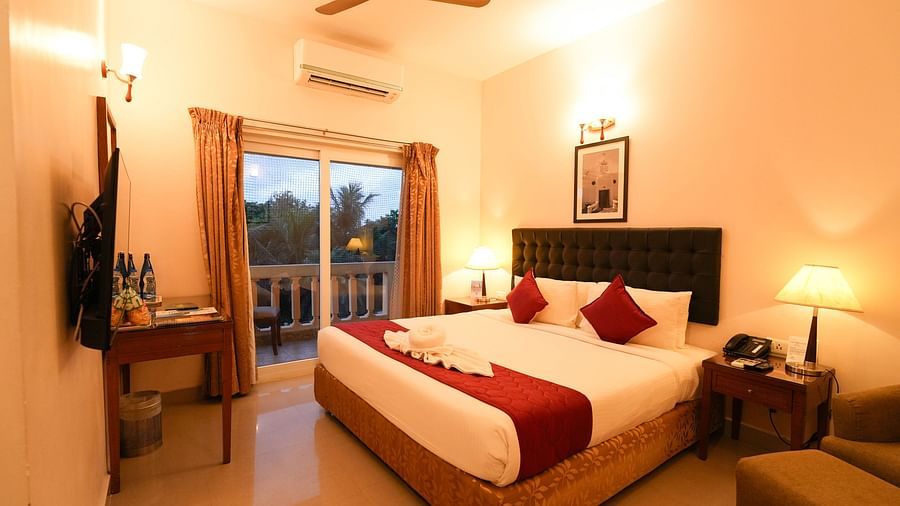 Image of Grandeur Pool View Suite featuring a plush bed facing the TV on the wall and the door to balcony next to the nightstand