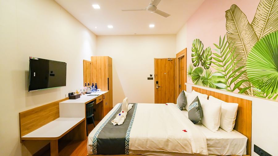 Image of bedroom featuring a plush bed in front of a wall decorated with wallpaper and a TV in the front