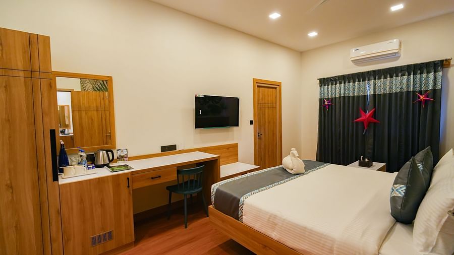 Image of a plush bed facing the TV mounted on the wall next to the wardrobe