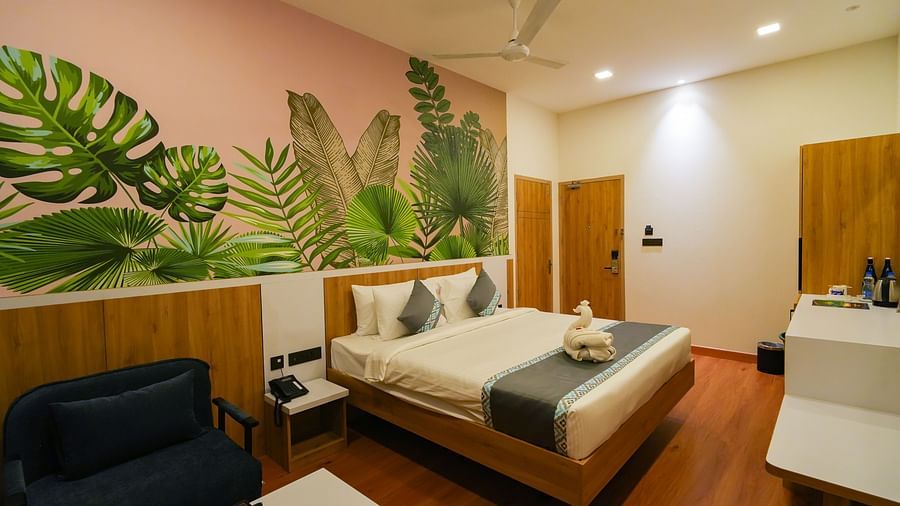 A warm-lit bedroom featuring a plush bed and a sitting space next to the nightstand