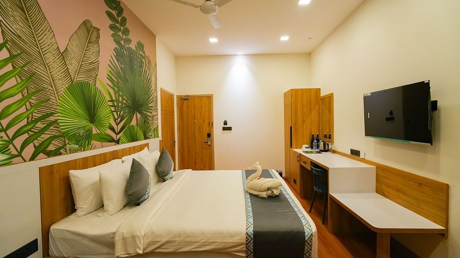 Image of a warm-lit bedroom featuring a plush bed facing the TV mounted on the wall 