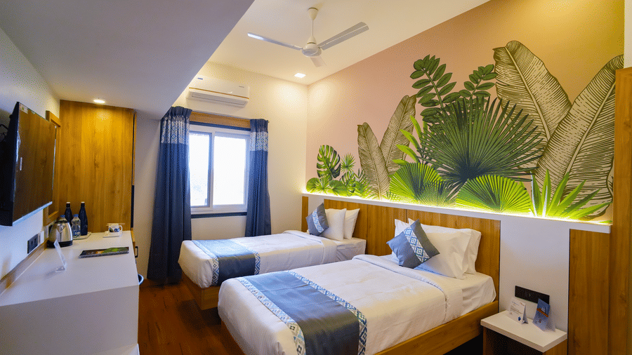A view of the deluxe twin room showing two beds and a feature wall with a bright, leafy design.