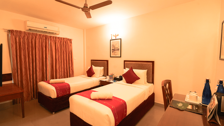 A wide view of the room with several beds, decorated in a warm color palette with red bedding accents.