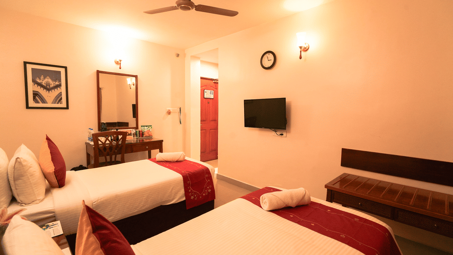 A warm-toned room featuring multiple beds (appears to be a triple or family room) with red and white bedding.