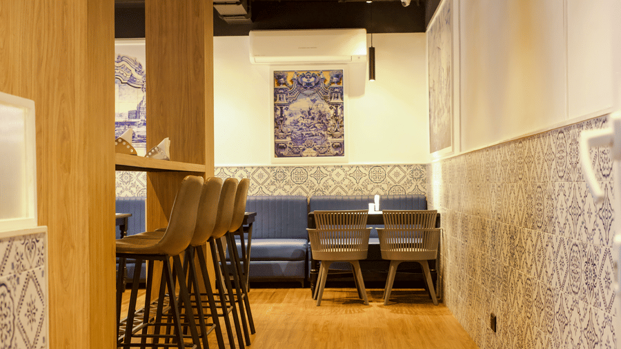 Dining space at MGM Vailankanni Residency with tables and chairs arranged near a wall decorated with patterned tiles and framed art.