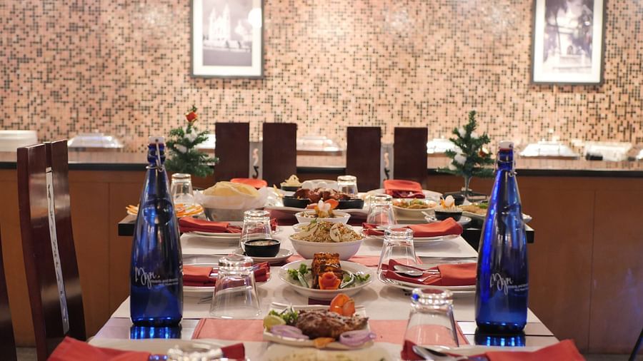 Various food placed on a large dining table along with labelled water bottles