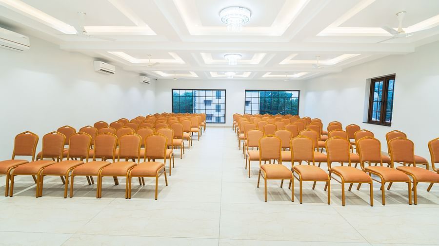 A banquet hall with orange chairs arranged in a theatre style seating arrangement - MGM Whispering Meadows