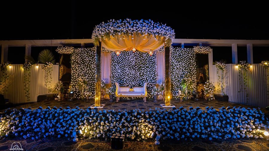 Beautifully decorated wedding stage illuminated with golden and blue lighting, adorned with flowers and a central seating arrangement at Voyage Milestone Hotel and Banquet Siliguri