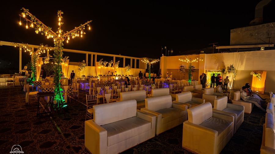 Chic outdoor event space at night with white lounge seating, warm lighting, and decorative tree installations at Voyage Milestone Hotel and Banquet Siliguri