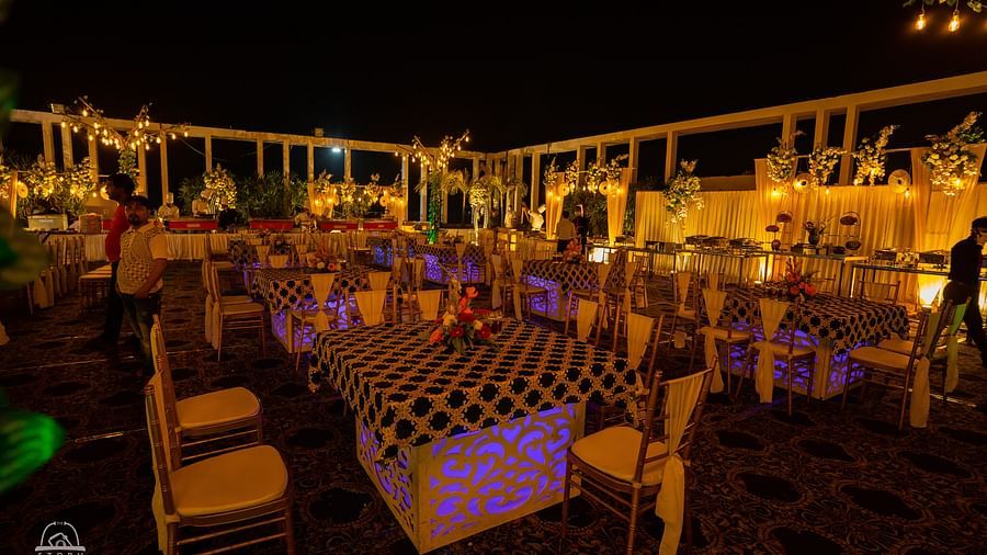 Outdoor evening event setting with festive lighting, banquet tables, and decorative elements under the night sky at Voyage Milestone Hotel and Banquet Siliguri