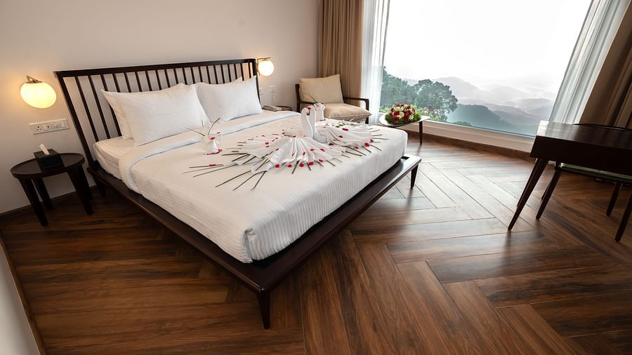 A bed in a room with a huge glass window | Misty Queen by Dimora, Kakkadampoyil