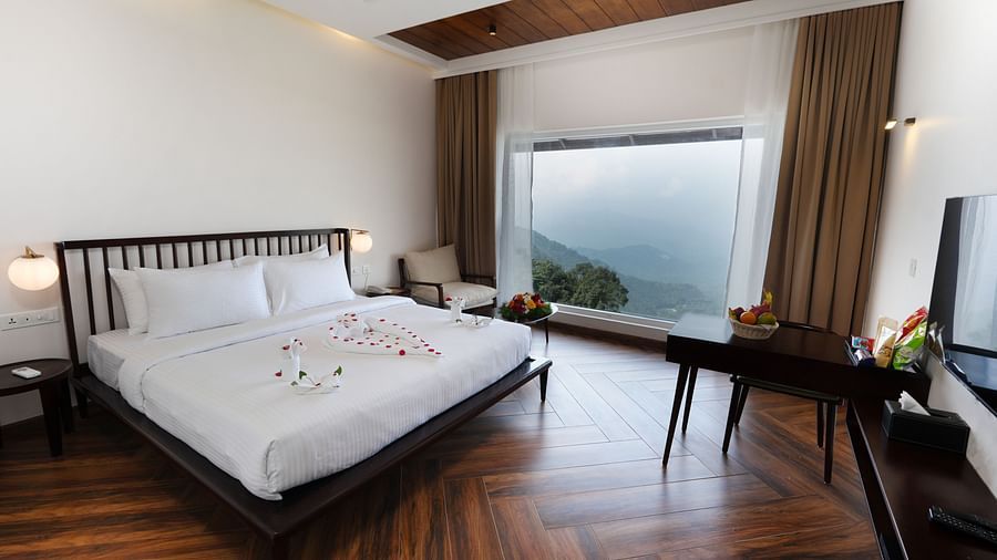 A bed in a room with a huge glass window | Misty Queen by Dimora, Kakkadampoyil