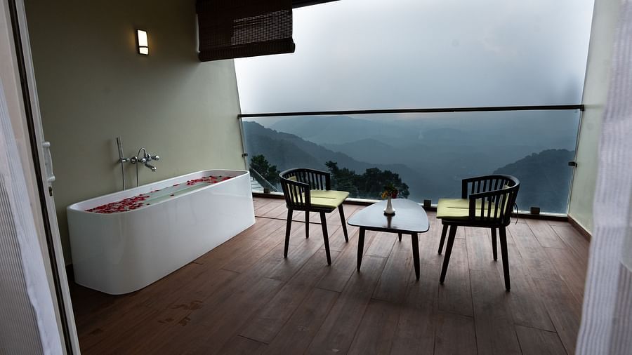 A table and two chairs in a balcony with mountain view | Misty Queen by Dimora, Kakkadampoyil