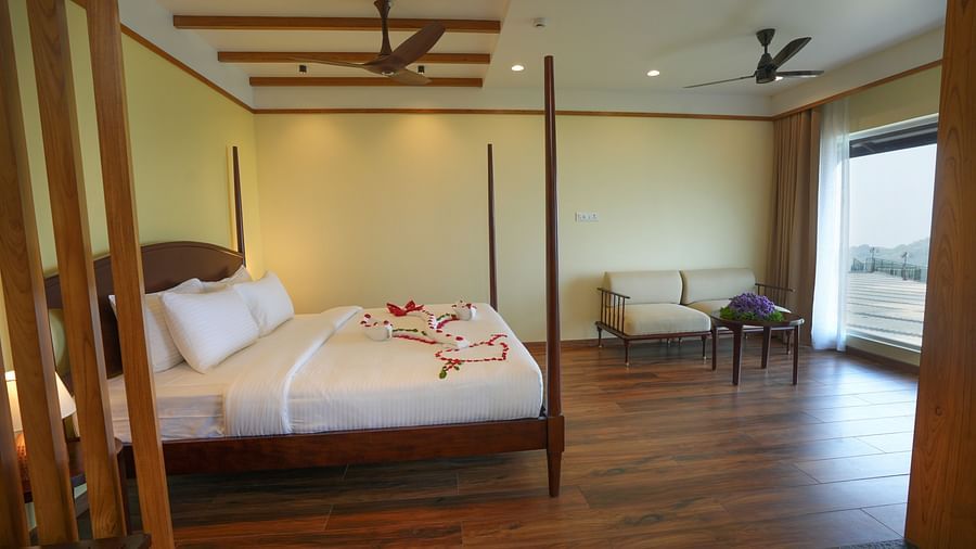 A side view of a room with a bed, sofa, table and a glass window | Misty Queen by Dimora, Kakkadampoyil
