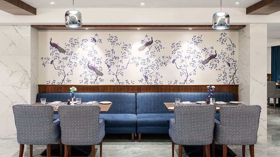 A beautiful image of a cosy corner seating arrangement with tables, chairs, and couches in our restaurant in Haridwar - MJ Sarovar Portico, Haridwar