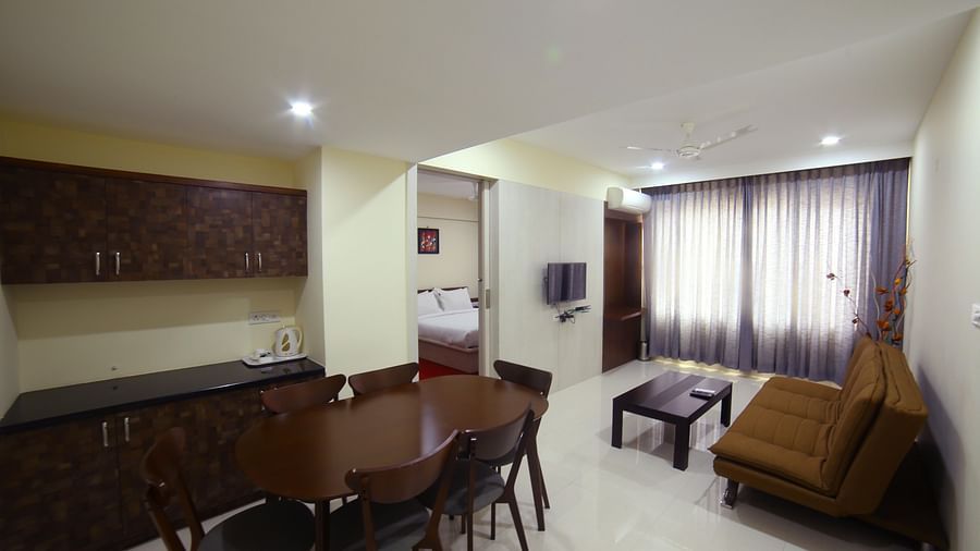A living area featuring a sofa a table kitchen counter and a dining area - Mysore Gate Hotel Bangalore