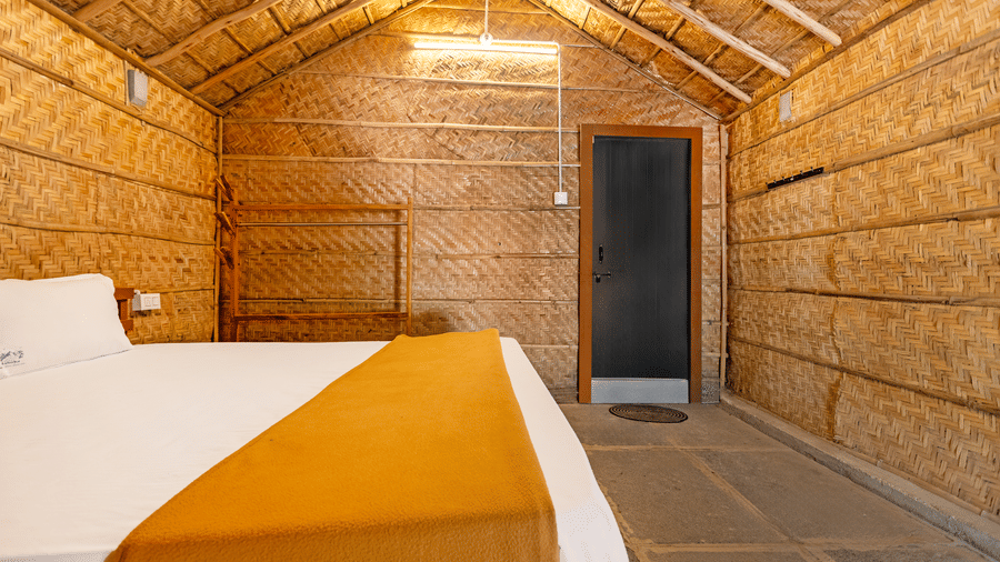 Close-up view of a cottage bedroom with textured woven wall panels and minimalist decor - Nature Trails Ashoka Resort Hampi