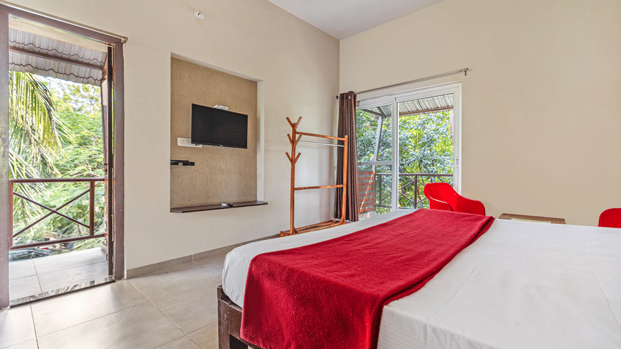 Modern bedroom interior highlighting the transition to a private balcony surrounded by lush greenery - Nature Trails Ashoka Resort Hampi