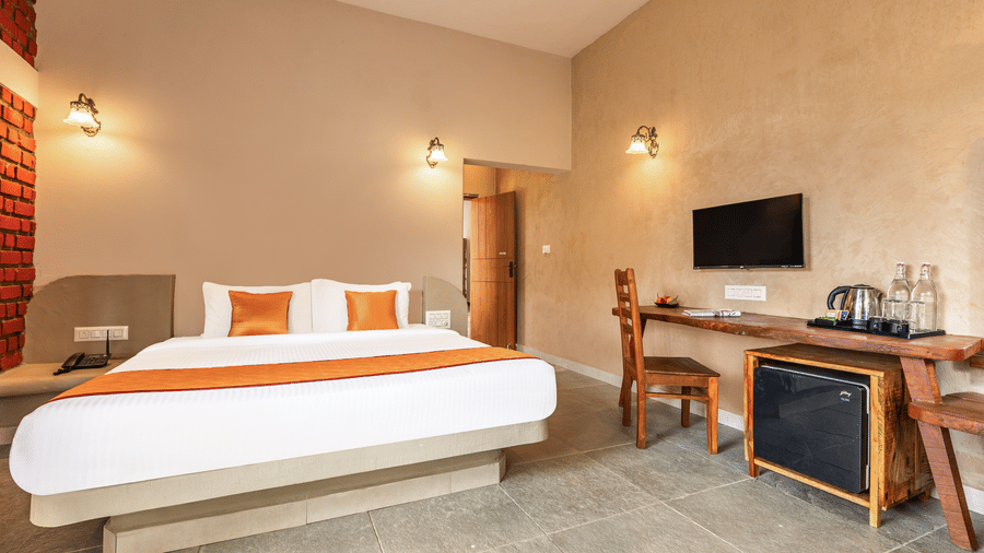 Modern premium bedroom with a floating bed design, warm ambient lighting, and work desk - Nature Trails Ashoka Resort Hampi