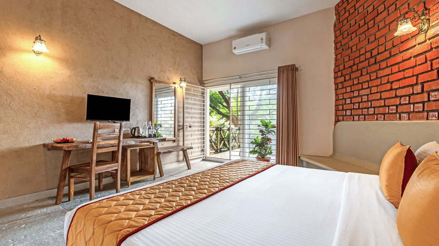Comfortable suite bedroom with air-conditioning and a view toward the balcony - Nature Trails Ashoka Resort Hampi