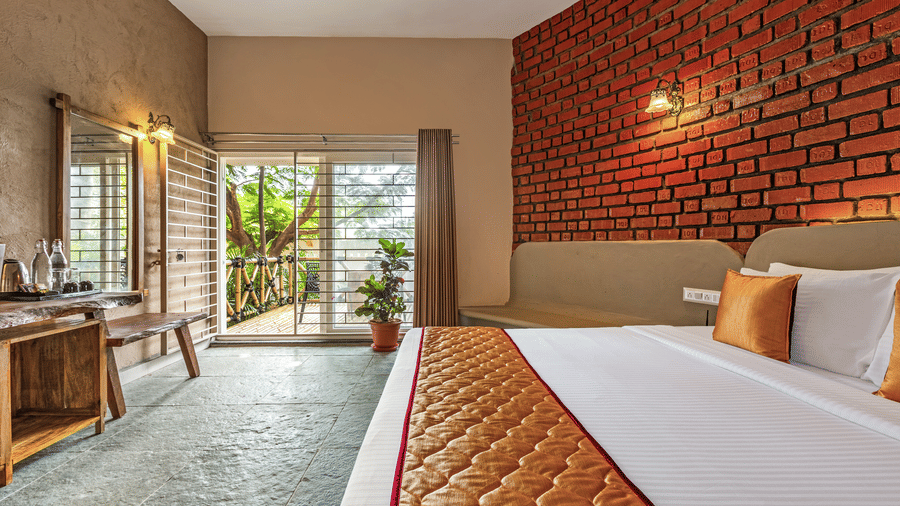 Perspective shot of a suite bedroom highlighting the natural light from the balcony - Nature Trails Ashoka Resort Hampi