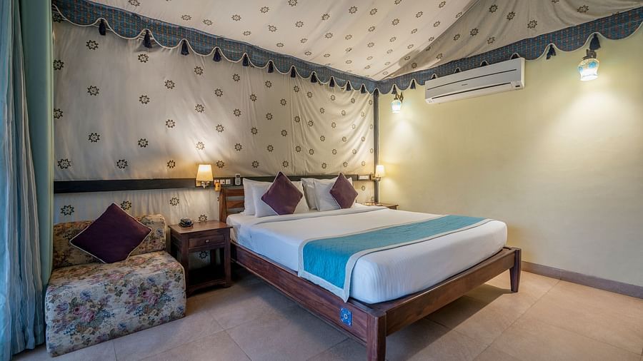 Glamps 2 - A luxurious bedroom with a canopy ceiling, patterned walls, and a scenic view through large windows.