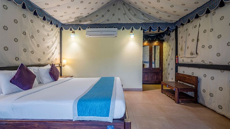 Glamps 4 - A luxurious bedroom with a canopy ceiling, patterned walls, and a scenic view through large windows.