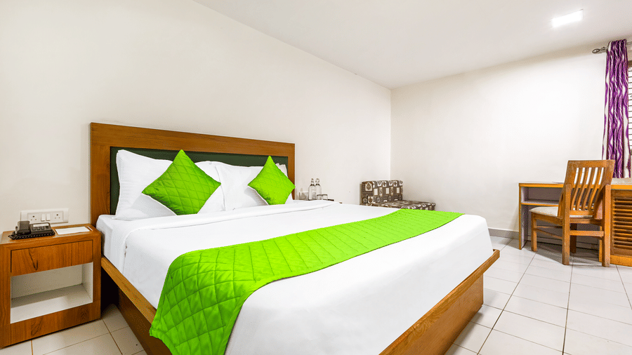 large bed with a wooden frame and matching headboard. The bed is made with white linens and a distinctive bright runner across the foot at Nature Trails Durshet.