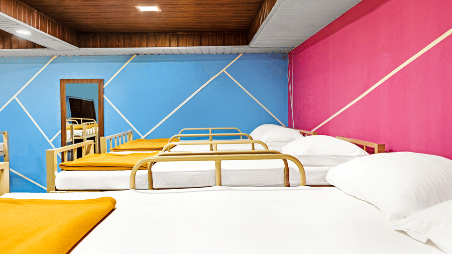 Nature Trails Kudalika 20 dom room with single metal-frame beds with white bedding and mustard blankets, blue and pink geometric painted walls and wood-panelled ceiling.
