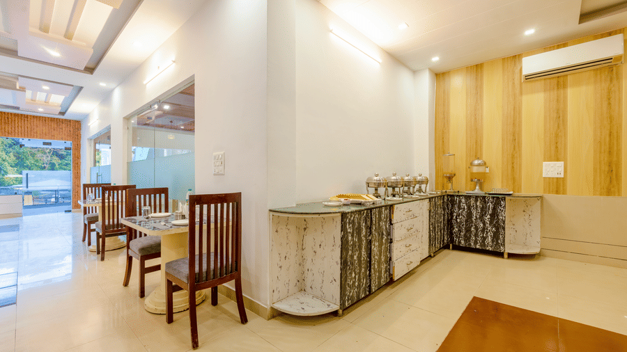 A clean and modern buffet area in a hotel restaurant with light wood panelling and tiled floors - Nature Trails Rishikesh