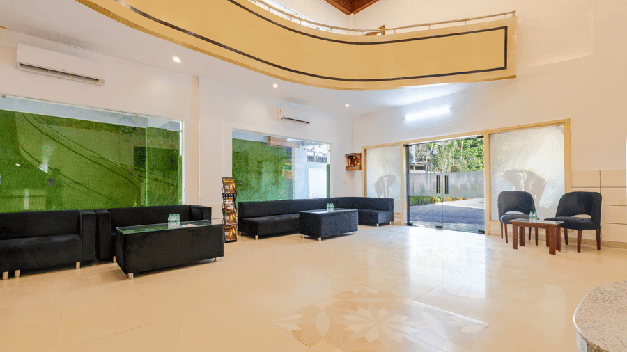 A spacious, brightly lit hotel lobby featuring black modern sofas and large glass windows - Nature Trails Rishikesh