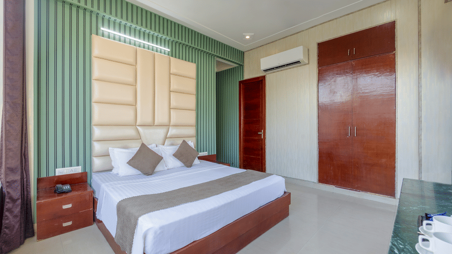A clean, minimalist bedroom with green accent walls and dark wood wardrobes - Nature Trails Rishikesh