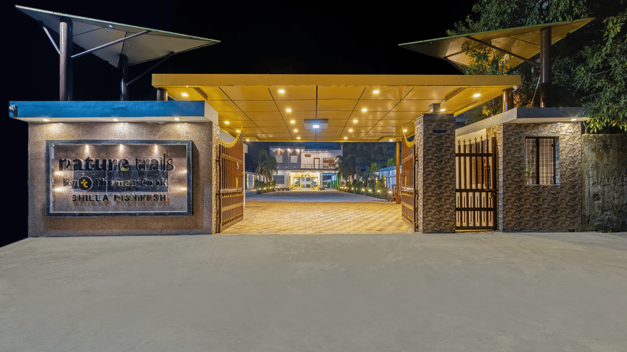 The illuminated main entrance gate and signage of the resort at night - Nature Trails Rishikesh