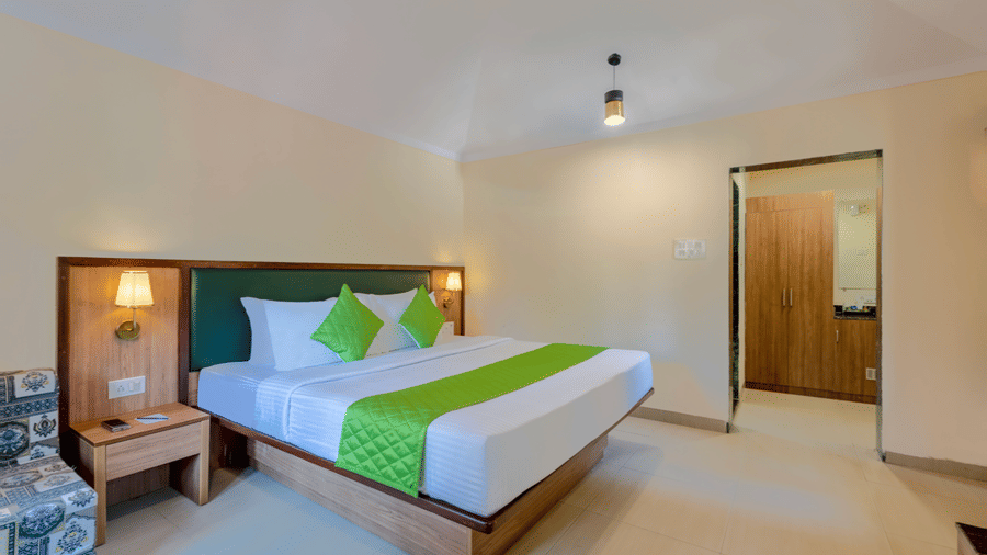 Angled view of a classic room bedroom with double bed, side table, and wardrobe area.