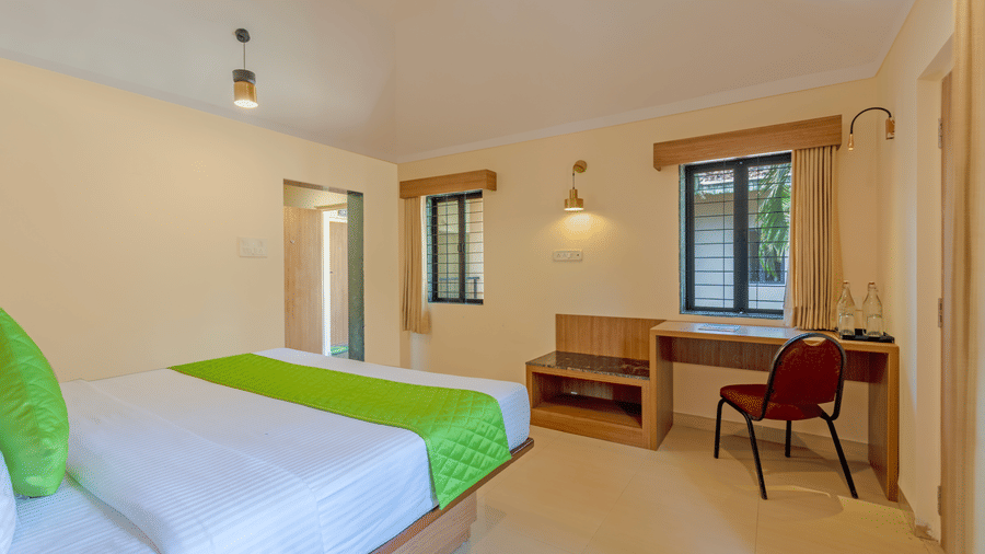 Classic room with a double bed, study desk, chair, and windows creating a bright interior.