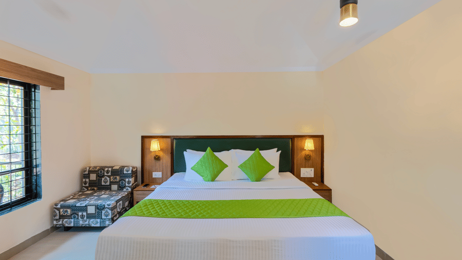 Front view of a classic room bed with green accents, bedside lamps, and minimal decor.