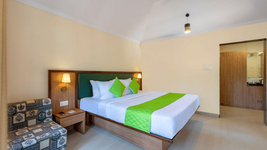 Spacious classic room with double bed, green cushions, seating area, and bedside lighting.