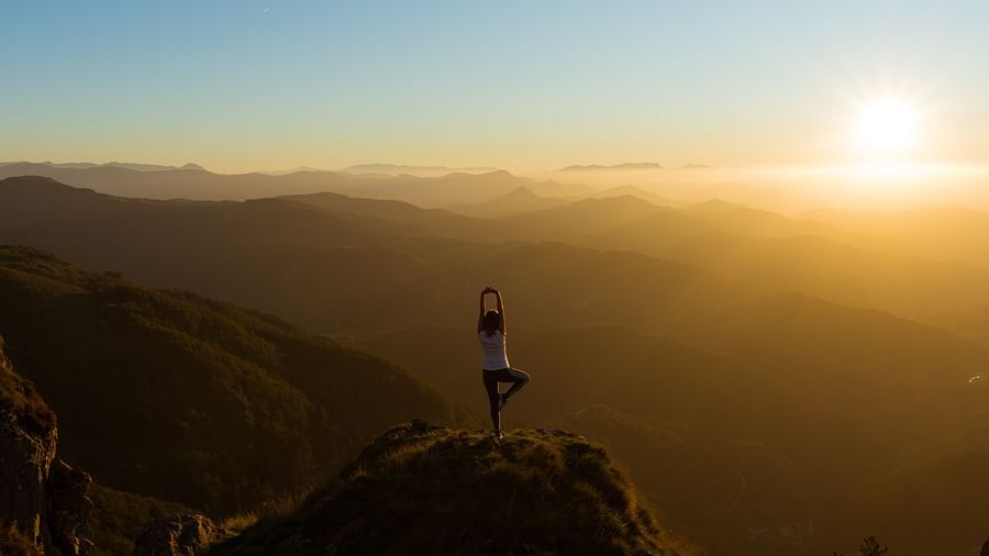 a person practicing yoga on hilltop during sunrise