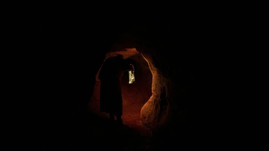 A dark cave featuring a silhouette of a person in dim light.