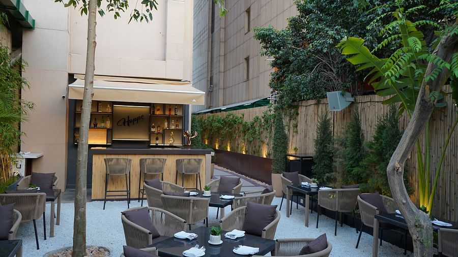 Guests at Nemesia enjoy an outdoor dining area with tables, chairs, and a bar area in the background.