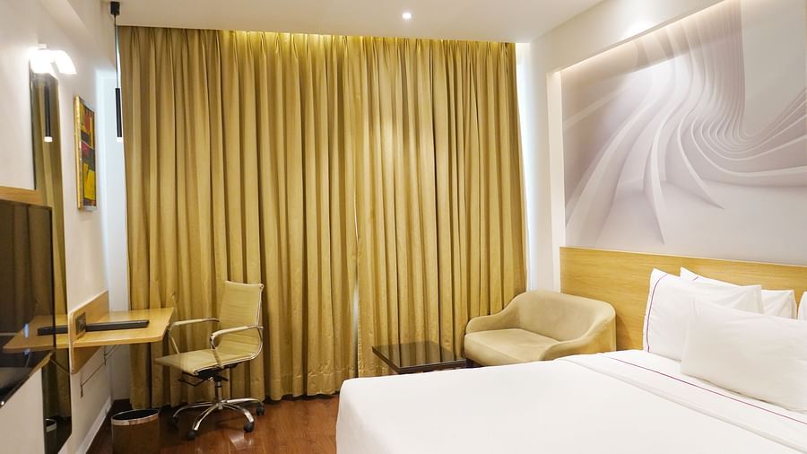 Comfortable guest room at Nemesia with a bed, modern decor, and floor-to-ceiling curtains along with the study desk.