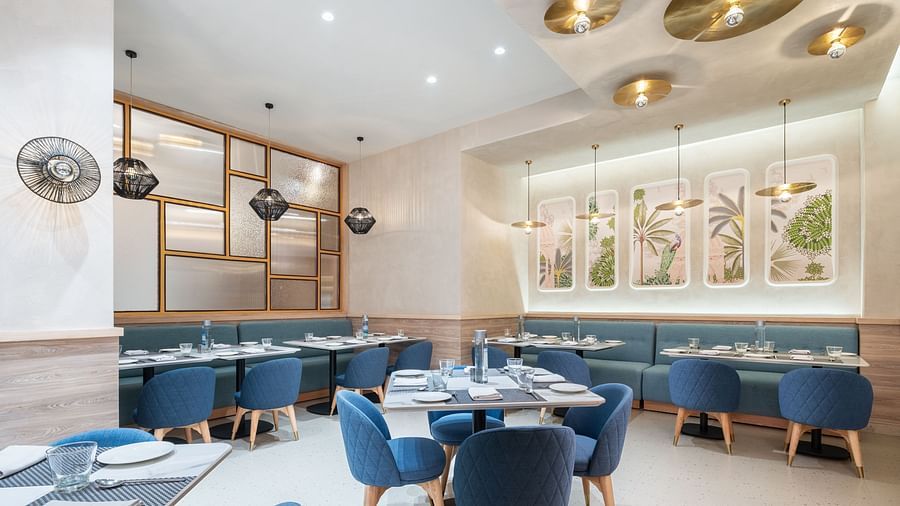A dining area with a marble floor and blue upholstered chairs.
