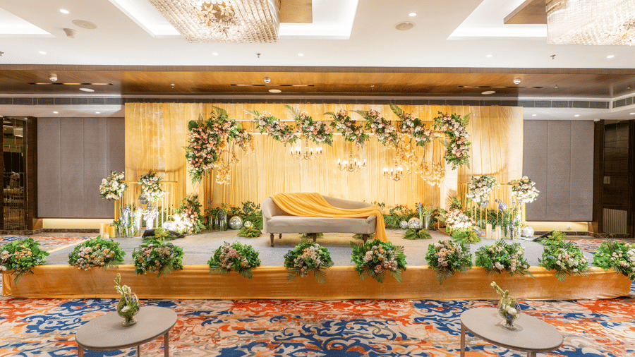 An event stage setup at Nirvana Sarovar Portico, Gorakhpur featuring a lounge couch, floral arrangements, and patterned carpet.