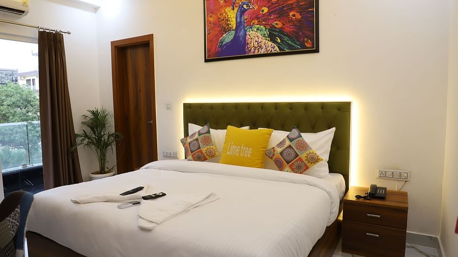 A room featuring a well decorated bed side drawer wall oainting and an AC - Opulent Inn