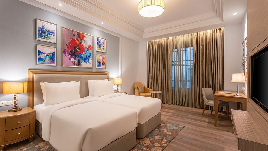 twins beds, a side table with a lamp, a work desk with a chair, and a television in one of the rooms at Park Plaza, Jalandhar