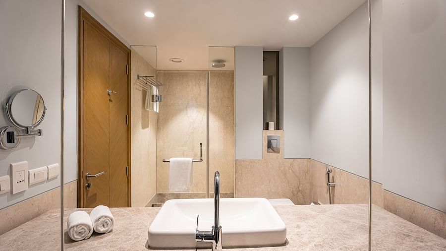 reflection of the wash basin and shower area from the mirror of the restroom in one of the rooms at Park Plaza, Jalandhar