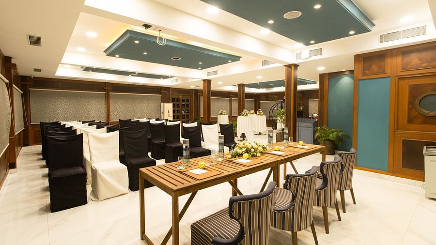 An elegant meeting room featuring a wooden conference table with striped chairs, accented by soft lighting and a sophisticated decor.